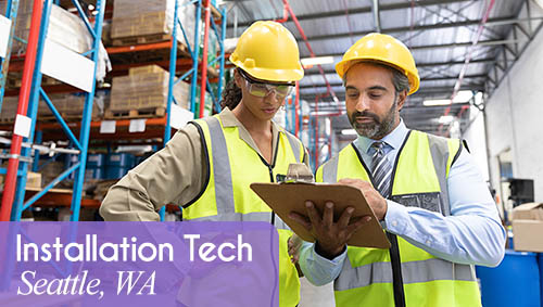 Image shows a man and a woman wearing protective gear and looking at a clipboard in a warehouse. Now Hiring an Installation Tech in Seattle, WA. All StarZ Staffing.