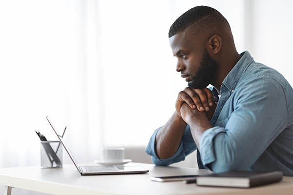 Image shows a man looking intently at a laptop. Find out how to use AI mock interviews to prepare for job interviews.