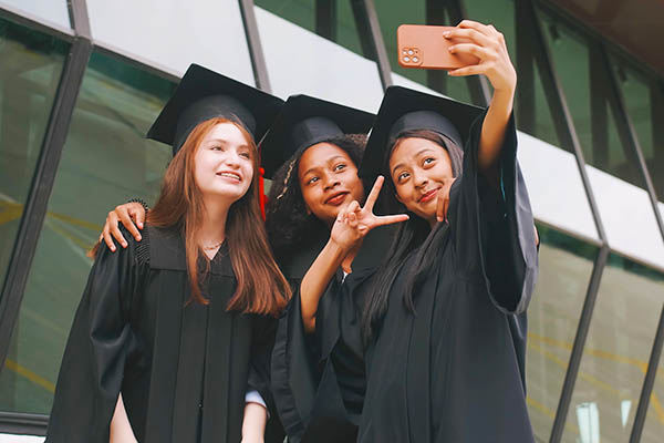 Image shows 3 girls taking a selfie at their graduation. All StarZ Staffing.