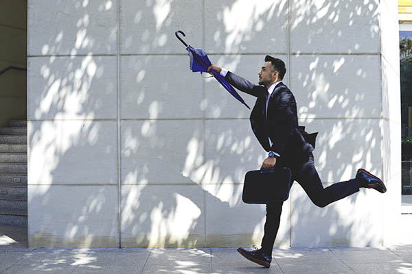 Image shows a man with an umbrella and briefcase running to catch the bus.