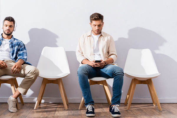 Image shows two bored male job seekers waiting in a waiting room.