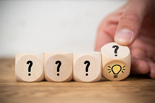 Image shows a four wood blocks with question marks on them. A hand lifts one to reveal a light bulb. Find out how second-chance employment can benefit your business.
